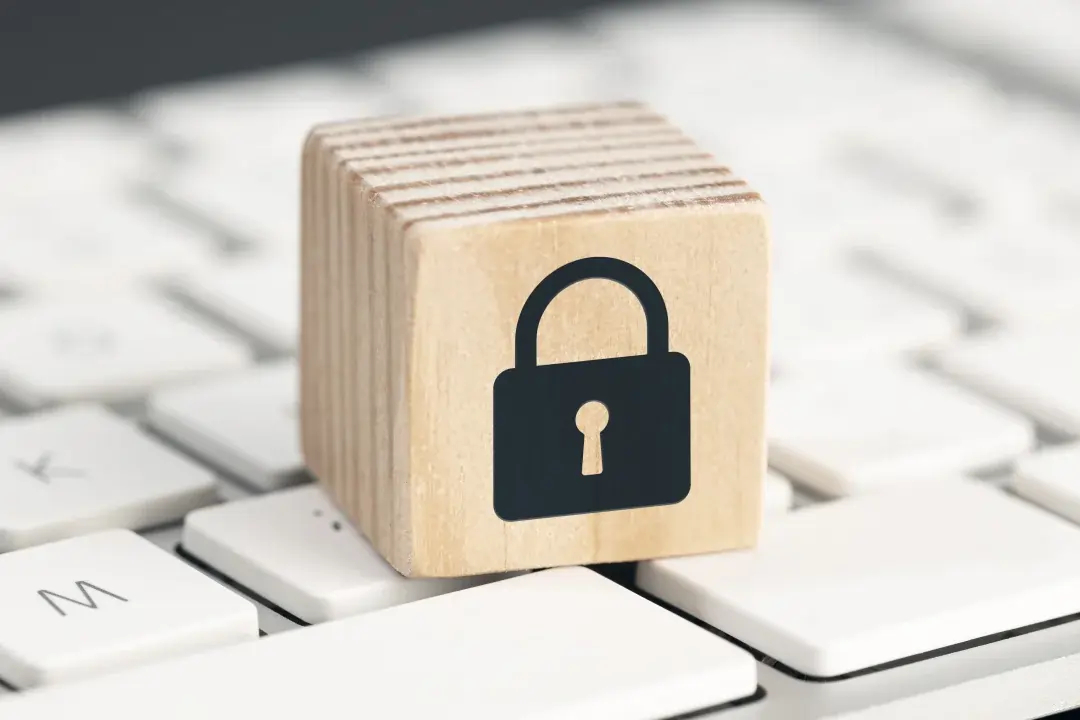 Persona trabajando en laptop con icono de candado, representando seguridad y privacidad de datos.